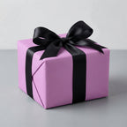 Opulent Orchid: Solid Color Gift Wrap on gift box with a black ribbon on a gray background