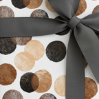 Modern minimalist wrapping paper with brown, black, and tan textured polka dots and a dark gray grosgrain ribbon bow.