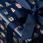 Navy blue gift box wrapped in insect-patterned wrapping paper with matching ribbon bow.