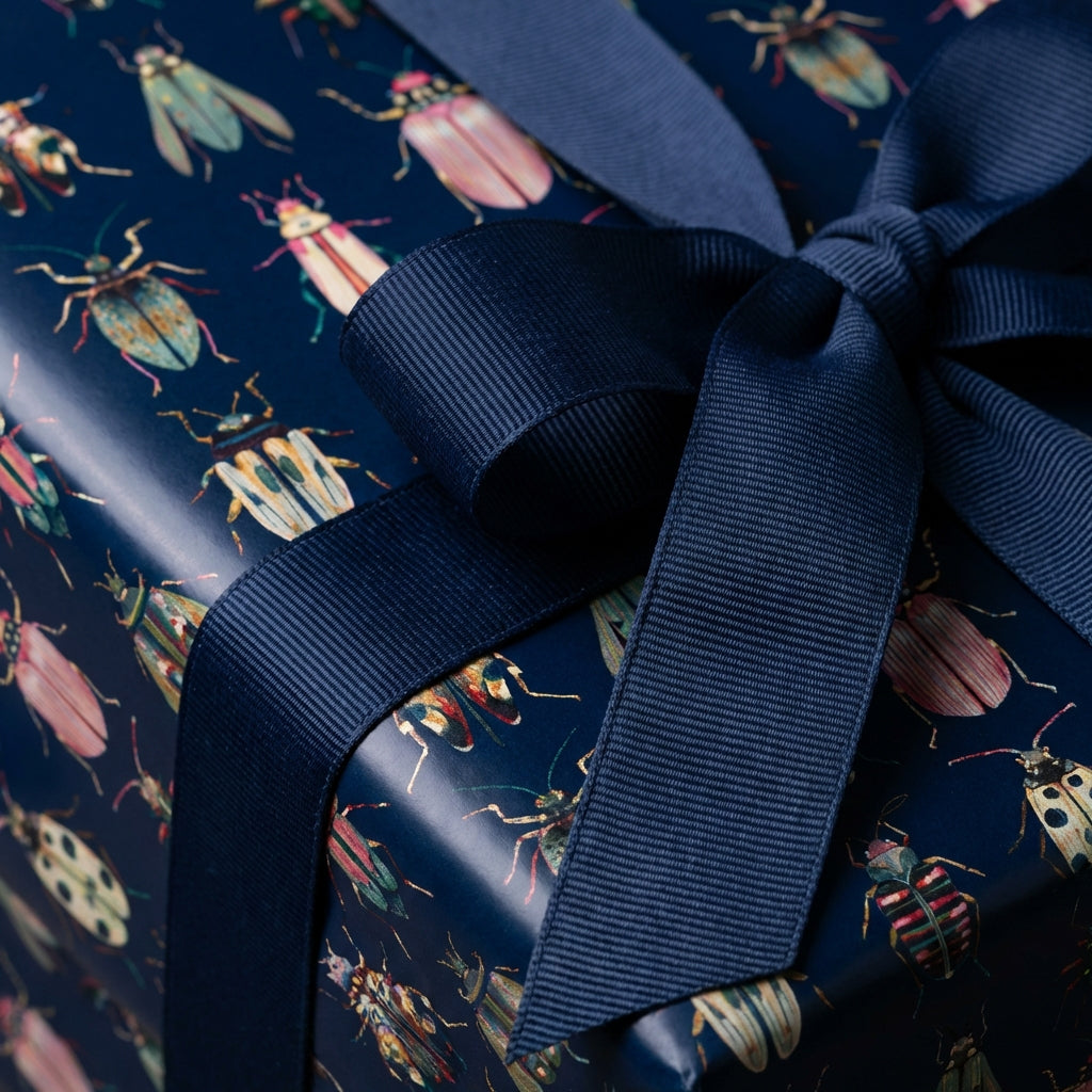 Navy blue gift box wrapped in insect-patterned wrapping paper with matching ribbon bow.