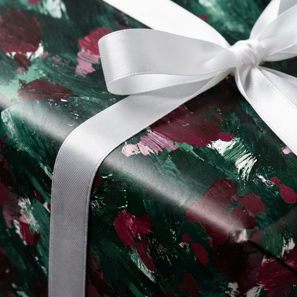 Elegant gift wrapped in dark floral wrapping paper with a white satin ribbon.