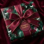 Wrapped Studios luxury gift wrap, featuring a modern floral pattern with a burgundy bow and gold trim.