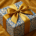 Luxury gift box with modern blue and gold mosaic wrapping paper and a satin gold ribbon by Wrapped Studios.