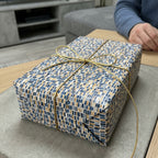 Luxury gift box with modern blue, gold, and grey mosaic pattern, tied with a metallic gold ribbon by Wrapped Studios.