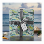 Modern waves wrapping paper in blues and greens with a grey ribbon and "A Touch of Serenity" tag, perfect for beach-themed gifts.