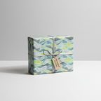 Modern abstract wave pattern wrapping paper with blue and green hues, tied with a gray ribbon and "Wrapped Studios" tag, perfect for any gift.