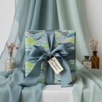 Modern abstract waves wrapping paper in green and teal with a silk dusty blue ribbon, perfect for luxury birthday or wedding gifts.