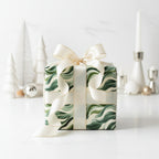 Elegant Christmas gift wrapped in modern green wave paper with satin ribbon.