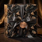 Luxury gift wrap by Wrapped Studios with abstract black and gold pattern, tied with gray satin ribbon.