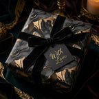 Elegant gift wrapped in black and gold marble paper with black velvet ribbon and "With Love" tag.