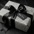 Modern black and white spotted wrapping paper with a luxury satin bow on a gift box by Wrapped Studios.