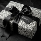 Modern black and white spotted wrapping paper with a luxury satin bow on a gift box by Wrapped Studios.
