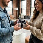 Smiling couple with gift in modern black and white dotted wrapping paper and black bow, by Wrapped Studios.