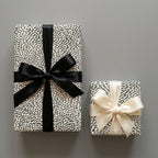 Minimalist black and white wrapping paper with satin bows. Luxury modern gift wrap by Wrapped Studios.