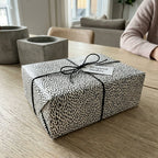 Minimalist black and white speckled wrapping paper on a gift box with black twine by Wrapped Studios.