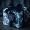Luxury blue abstract wrapping paper with a navy velvet bow on a gift box by Wrapped Studios.