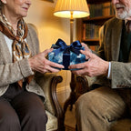 Elderly couple sharing an anniversary gift in luxury blue wrapping paper by Wrapped Studios.