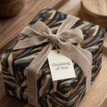 Wrapped present with modern abstract wrapping paper, velvet bow, and "Thinking of You" tag.