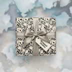 Luxury neutral gift wrap with a modern black and beige abstract pattern, tied with a silky silver ribbon and gift tag, perfect for any occasion.