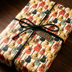 Retro guitar wrapping paper by Wrapped Studios with a black twine bow and "Rock On" tag.