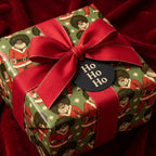 Black Santa Christmas wrapping paper with red bow and Ho Ho Ho tag by Wrapped Studios.