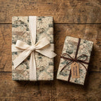 Vintage map wrapping paper on gifts with cream ribbon and tag on rustic wood table, by Wrapped Studios.
