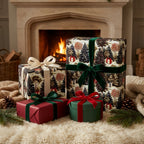 Luxury woodland Christmas wrapping paper with velvet ribbons by a cozy fireplace. By Wrapped Studios.
