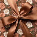 Elegant vintage floral wrapping paper with cream roses and a brown satin bow, by Wrapped Studios.