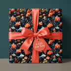 Elegant gift in floral wrapping paper with coral ribbon. "A Gift For You" tag. Wrapped Studios.