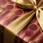 Luxury red and gold holiday wrapping paper with a satin bow by Wrapped Studios.