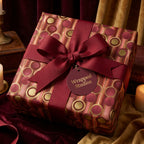 Luxury burgundy and gold holiday wrapping paper with a red ribbon bow and gift tag by Wrapped Studios.