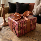 Burgundy and gold retro geometric luxury gift wrap with a copper satin bow by Wrapped Studios.