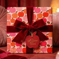 Cute apple pattern wrapping paper with a red velvet bow and gift tag by Wrapped Studios.