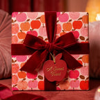 Cute apple pattern wrapping paper with a red velvet bow and gift tag by Wrapped Studios.
