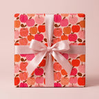 Cute pink apple wrapping paper with a satin ribbon bow, playful birthday gift wrap by Wrapped Studios.