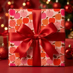 Red and pink apple pattern Christmas gift wrap with a satin ribbon bow by Wrapped Studios.