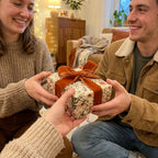 Couple exchanging a gift wrapped in vintage floral wrapping paper with a rust velvet bow by Wrapped Studios.