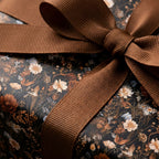 Moody vintage floral wrapping paper with a rustic brown ribbon bow by Wrapped Studios.