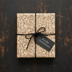 Elegant gift wrapped in brown floral wrapping paper with a black cord bow and a "For the Gentleman" tag.