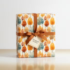 Square gift wrapped in watercolor autumnal tree wrapping paper with brown ribbon and bow.