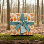 Elegant gift wrapped in autumnal tree print wrapping paper with teal ribbon.