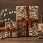 Elegant gifts wrapped in floral wrapping paper with brown velvet ribbons on a rustic wooden surface.