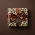 Elegant gift with vintage floral wrapping paper and brown satin ribbon on matching brown background.
