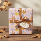 Dusty rose birthday wrapping paper with autumn leaves and a gold ribbon.
