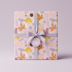 Gift wrapped in autumnal-themed wrapping paper with leaves and acorns, finished with a lilac ribbon.