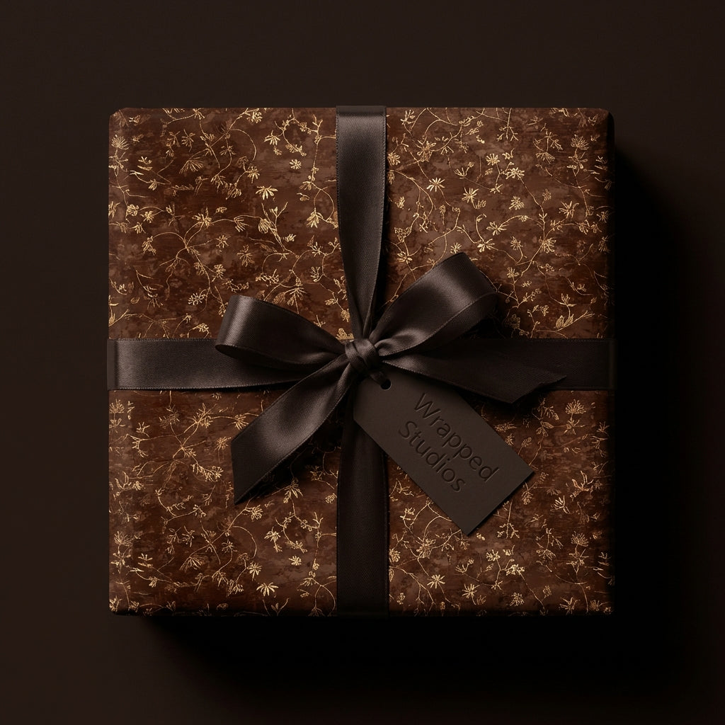 Elegant floral wrapping paper in brown with gold accents and a dark ribbon.