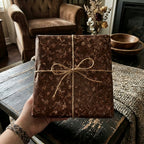 Hand holding a gift wrapped in floral wrapping paper with a rustic twine bow.