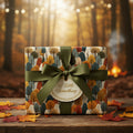 Autumn-themed gift wrapped in tree pattern wrapping paper with green ribbon and fall leaves.