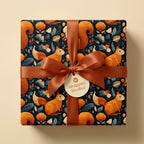 Square gift box wrapped in autumn-themed wrapping paper with squirrels and flowers, finished with a brown ribbon and bow.