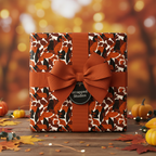 Square gift box in autumn leaf print wrapping paper with burnt orange ribbon and bow.